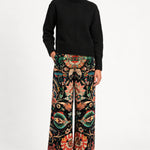Model wearing Aveline Black Aubussy printed velvet wide-leg pants with a black sweater, front view