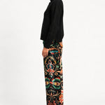 Side view of model wearing Aveline Black Aubussy pants with a black turtleneck