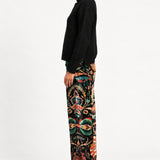 Side view of model wearing Aveline Black Aubussy pants with a black turtleneck