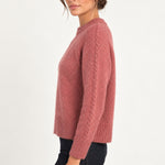 Clémence cable-detail crewneck sweater in Rosewood, side model view on an ivory backdrop