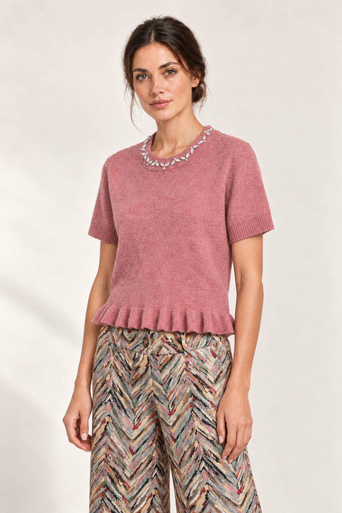Three-quarter view of the Émeline Rose Jeweled Ruffle-Hem Sweater paired with Héloïse Multico Chevron pants