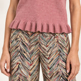 Detail of the Émeline Rose sweater's ribbed ruffle hem above Héloïse Multico Chevron jacquard pants
