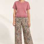 Full outfit featuring the Émeline Rose Jeweled Ruffle-Hem Sweater, Héloïse Multico Chevron wide-leg pants and black flats on an ivory backdrop