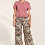 Full outfit featuring the Émeline Rose Jeweled Ruffle-Hem Sweater, Héloïse Multico Chevron wide-leg pants and black flats on an ivory backdrop