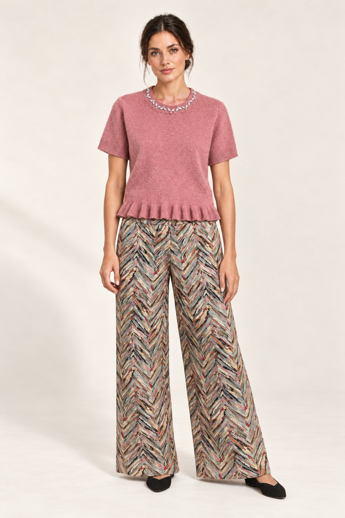 Full outfit featuring the Émeline Rose Jeweled Ruffle-Hem Sweater, Héloïse Multico Chevron wide-leg pants and black flats on an ivory backdrop