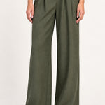 Perrine military olive pleated wide-leg pants, detail view on a model against an ivory studio background