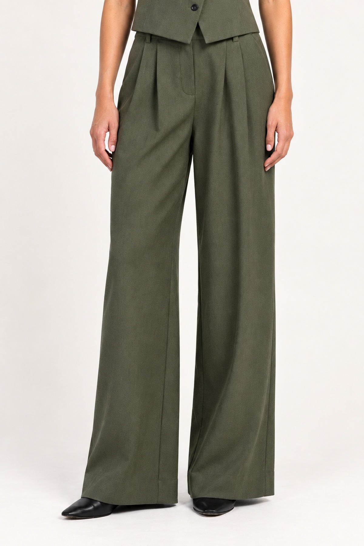 Perrine military olive pleated wide-leg pants, detail view on a model against an ivory studio background