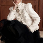Regent Pearl-Embellished Bouclé Jacket — Ivory jacket seated styling view with stand collar, braided trim and faux-pearl detail
