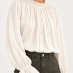 Sabine écru lace-trim blouse, detail view showing ruffled collar and fluted cuffs on a model against an ivory background