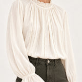 Sabine écru lace-trim blouse, detail view showing ruffled collar and fluted cuffs on a model against an ivory background